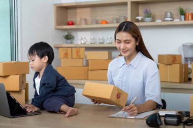 Kendini işine adamış bir anne çevrimiçi satış işini ve ebeveynliğini dengeler ve modern iş hayatı entegrasyonunu gösterir..