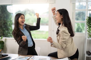 İki heyecanlı iş ortağı zaferi kutlarken ofis ortamında yumruklarını kaldırdı..