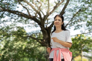 Son sınıf öğrencisi bir kadın parkta güvenle yürüyor, sağlığı ve doğa içinde aktif bir yaşam tarzını teşvik ediyor..
