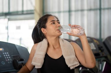 Kendini adamış bir antrenör, yoğun bir beden eğitimi seansından sonra sağlıklı ve sağlıklı olması için genç bir kadının su içmesine yardım eder..