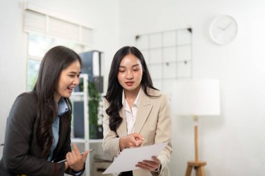 İş ortakları, önemli belgeleri incelerken, takım çalışması ve işbirliğini ön plana çıkarırken, odaklı bir tartışmaya giriştiler..