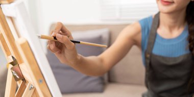 Genç bir kadın, resim sehpasında tutkulu bir şekilde resim yapar, yaratıcılığını kapalı bir ortamda ifade eder..