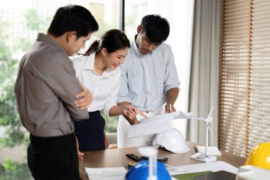 Sürdürülebilir bir girişimin proje ayrıntılarını analiz eden profesyoneller, takım çalışmasının gösterilmesi ve yeşil çözümlere bağlılığın gösterilmesi.