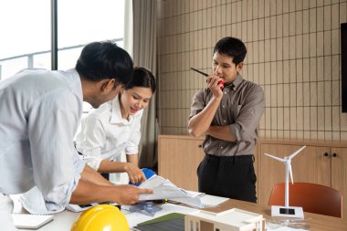 Sürdürülebilir proje tasarımlarını, modern bir çalışma alanında işbirliği ve yenilik sergilemeyi tartışan çeşitli profesyonellerden oluşan bir ekip.