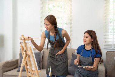 İki kadın sanatsal yeteneklerini ifade ederek ve sıcak bir atmosferde birbirlerine eşlik ederek yaratıcı bir resim seansına katılıyorlar..