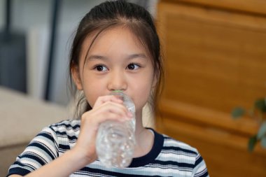 Genç bir kız içme suyundan zevk alır, günlük hayatta susuzluğun ve sağlığın önemini vurgular..