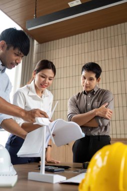 Bir grup profesyonel, sürdürülebilir proje stratejileri ve modern bir ofiste işbirliği üzerine bir tartışmaya girişti..
