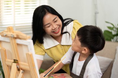 Bir anne, resim yaparken oğluyla keyifli bir anı paylaşır. Yaratıcılığı ve besleyici bir çevrede bağlantıyı teşvik eder..