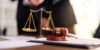 Masadaki tokmak ve yasal terazinin yakın çekimi profesyonel bir ortamda adaleti ve hukuki işleyişi simgeliyor..