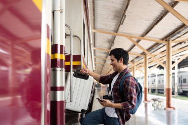 Genç bir adam neşeli bir şekilde bavulunu trene yüklüyor, heyecanlı bir yolculuğa hazırlanıyor..