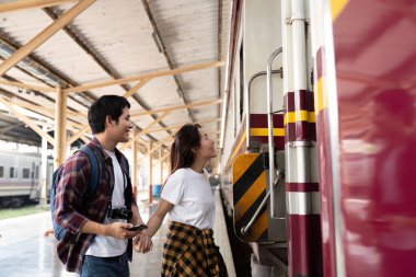 Genç bir çift mutlu bir şekilde trene biniyor, seyahat ve macera için heyecanlarını sergiliyorlar..