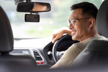 Neşeli bir adam, partneri yanında otururken eğlencesine araba sürmekten zevk alır..