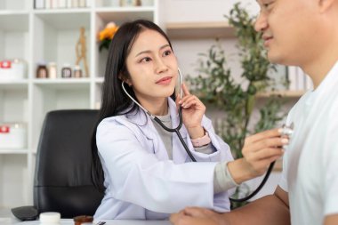 Bir doktor, klinik ortamında hasta sağlığını sağlamak için steteskop kullanarak rutin bir kontrol yapar..