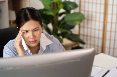 Genç bir kadın bilgisayar ekranında, modern bir ofiste ofis sendromu ile ilgili rahatsızlık ve stres belirtileri gösteriyor..