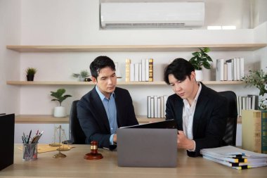 Bir avukat ve müvekkil, şık bir ofis ortamında önemli yasal belgeleri inceleyerek ayrıntılı bir tartışmaya girişirler..