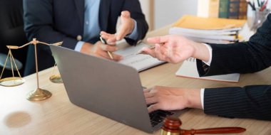 Bir avukat ve müvekkil, modern ofis ortamında önemli yasal belgeleri gözden geçirir..