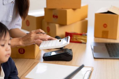 Bir anne mali görevler için hesap makinesi kullanırken, oğlu da ailenin ve iş sorumluluklarının entegrasyonunu ön plana çıkarıyor..