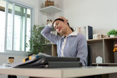 Genç bir profesyonel, ofis sendromuna bağlı fiziksel gerginliği göstermek için masasında boynunu uzatıyor..