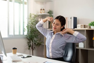 Profesyonel bir ortamda çalışan bir kadın, yoğun bir iş gününde kollarını uzatarak rahatlık ve rahatlığı teşvik eder..