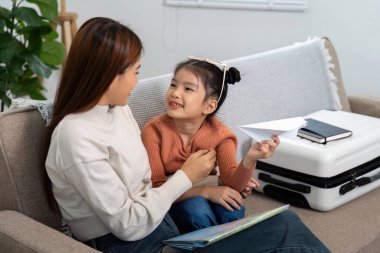 Bir anne ve kızı arasında kağıt uçakla oynarken kahkahalar atarak seyahat rüyalarını sembolize eden eğlenceli bir etkileşim..