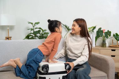 Kahkaha ve sevgiyle dolu bir bavul hazırlayan bir anne ve kızın seyahat maceralarına hazırlandığı hoş bir sahne..