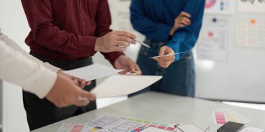 UX ve UI tasarımcılarından oluşan bir ekip, ortak bir toplantıda tasarım kavramlarını ve çizimleri inceleyerek yaratıcılığı teşvik ediyorlar..