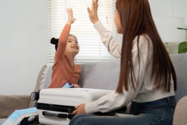 Neşeli bir anne ve kız, yaklaşan seyahat planlarını coşkulu bir beşlikle kutluyor..
