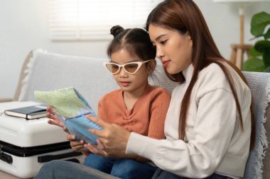 Bir anne ve kızı bir harita okurken bir keşif anını paylaşıyor, coşkuyla seyahat yolculuklarını planlıyorlar..