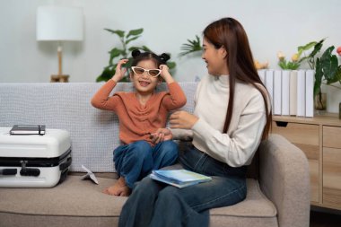 Anne-kız olarak neşeli bir an. Güneş gözlüklerini denerken heyecan verici bir aile tatili için bavullarını hazırlıyorlar..