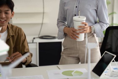 Çeşitli bir ekip sürdürülebilirlik stratejilerini tartışıyor, modern ofis ortamında yenilenebilir enerji projelerine odaklanıyor.