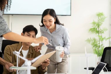 Bir grup genç profesyonel ESG planları üzerinde işbirliği yapıyor, parlak ve modern ofis ortamında görüşlerini ve fikirlerini paylaşıyorlar.