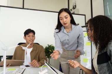 Çeşitli bir ekip, çevre dostu çözümler ve işbirliği üzerine odaklanarak, modern ofis ortamında sürdürülebilirlik stratejilerini tartışıyor..