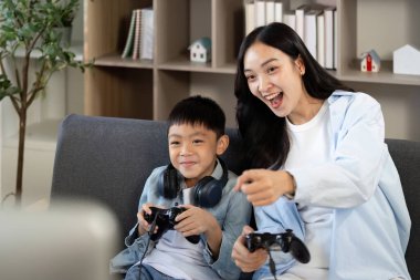 Bir anne ve oğlu oyun oynarken eğlenceli bir anı paylaşıyor. Oyun oynayarak aile bağlarının neşesini vurguluyorlar..