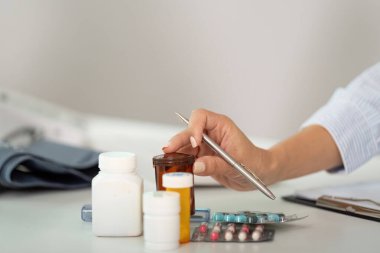 Sağlık görevlisi, ilaç yönetimi ve hasta bakımını vurgulayarak, çeşitli reçeteli ilaç şişelerini dikkatlice düzenler..