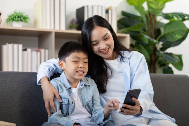 Bir anne ve oğlu, akıllı telefon kullanarak aile bağlarını ve dijital etkileşimlerini ön plana çıkarırken neşeli bir anı paylaşıyorlar..