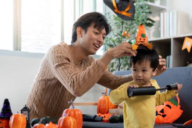 Bir baba, balkabakları ve süslemelerle çevrili bir cadılar bayramı şapkası yapması için küçük oğluna yardım eder, yaratıcılığı ve bağ kurmayı teşvik eder..