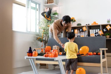 Bir baba ve oğul Cadılar Bayramı için dekorasyon yaparlar, balkabakları ve renkli dekorlarla dolu neşeli bir ortam yaratırlar..