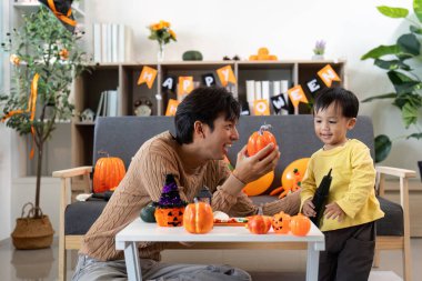 Bir baba ve oğul Cadılar Bayramı için balkabakları süsleyerek keyifli bir anı paylaşıyor, etrafı şenlikli süslemelerle çevrili..