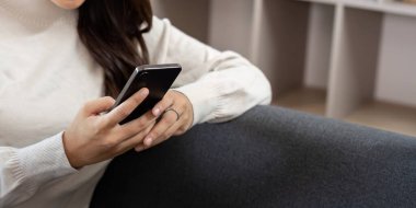 Genç bir kadın akıllı telefonuyla meşgul, modern ev ortamında rahat bir anın tadını çıkarıyor..