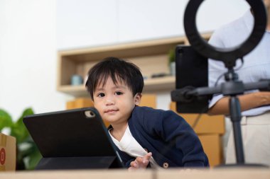 Anne işe hazırlanırken, aile ve iş hayatının karışımını gösteren bir tablete merakla bakan bir çocuk..