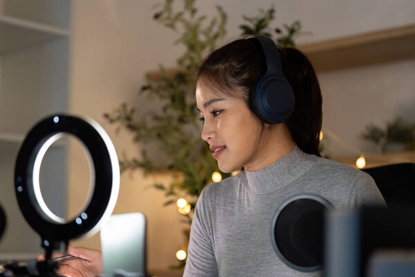 A woman with headphones smiles as she prepares for her podcast recording, surrounded by a cozy and inviting atmosphere.