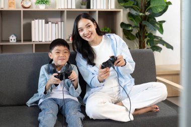 Bir anne ve oğlu birlikte oyun oynamaktan zevk alır. Kanepede eğlenceli ve interaktif bir aile anı yaşarlar..