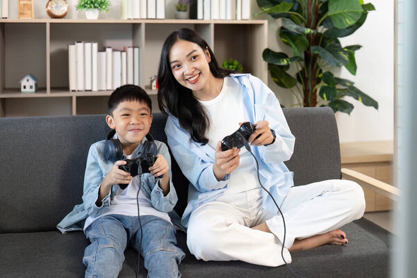 Мать и ее сын наслаждаются игрой вместе, демонстрируя веселый и интерактивный семейный момент на диване.