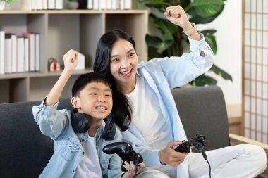 Bir anne ve oğlu video oyunları oynarken heyecanla neşe içinde neşe dolu aile ilişkilerini vurguluyor..