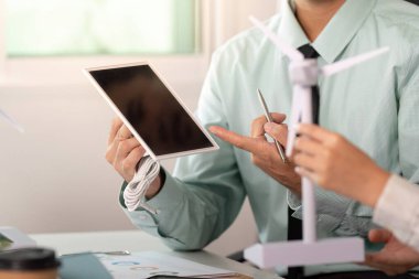 Bir profesyonel, sürdürülebilirliği vurgulayarak, bir iş ortamında ESG stratejilerini tartışırken yenilenebilir enerji modeline işaret eder.