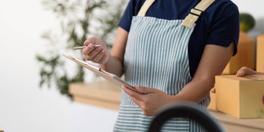 İki kadın, modern bir çalışma alanında lojistik ve notları bir pano ve akıllı telefonla gözden geçiriyorlar..