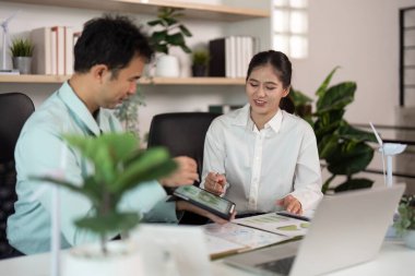 Profesyoneller, modern ofis ortamında sürdürülebilirlik ve kurumsal yönetim stratejilerini tartışan ESG girişimlerinde işbirliği yaparlar..