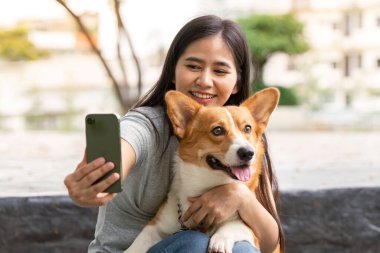 Bir kadın Corgisiyle selfie çekerken gülümser, neşeli bir arkadaşlık ve eğlence anı yakalar..