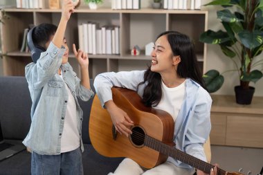 Bir anne ve oğul, anne gitar çalarken anne ve oğul neşeyle dans eder, yaratıcılığı ve bağlantıyı kutlar..