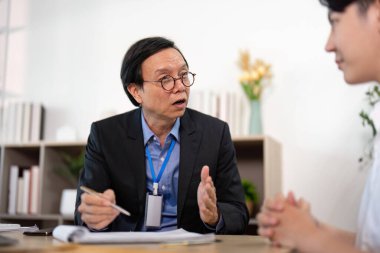 Bir sigorta acentesi, politika detaylarını müşteriye tutkuyla açıklar. Modern bir ofise anlayış ve güveni artırır..